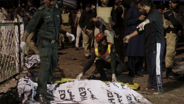 Rescue workers move a body from the site of a blast outside a public park in Lahore, Pakistan - اسپوتنیک ایران  