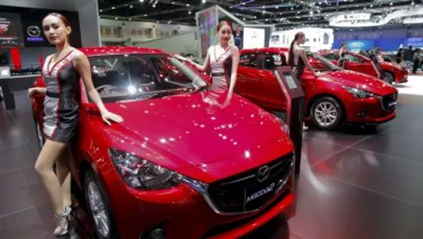 Модели позируют около автомобиля Mazda 2 на Международном автосалоне в Бангкоке