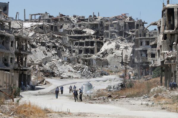 کارگران در حال جمع آوری قطعات ساختمان ویران شده در حمص - اسپوتنیک ایران  