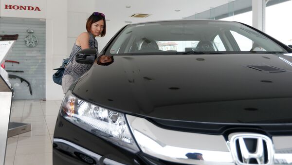 In this Dec. 22, 2014 photo, a woman checks out a new Honda City at a Honda showroom in Petaling Jaya, Malaysia - اسپوتنیک ایران  