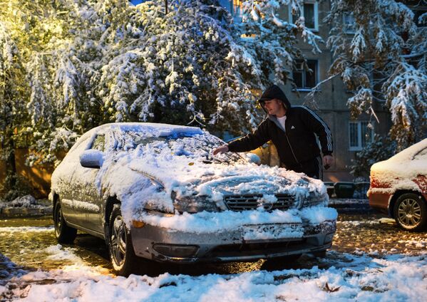 مردی در حال پاک کردن خودروی خود از اولین برف در اومسک - اسپوتنیک ایران  