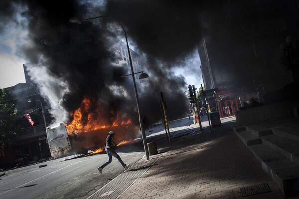 اتوبوسی که در زمان درگیری  دانشجویان با پلیس در ژوهانسبورگ آفریقای جنوبی به آتش کشیده شد - اسپوتنیک ایران  