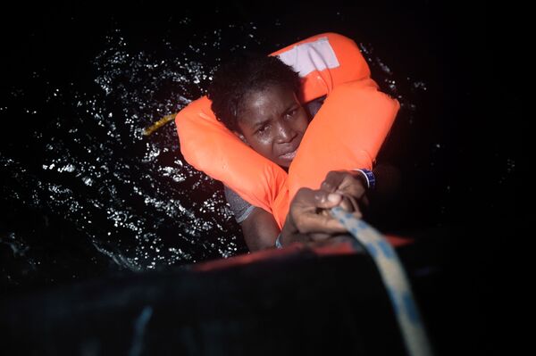 دختری آویزان از طناب در زمان عملیات  نجات کشتی در حال غرق پناهجویان  در سواحل لیبی - اسپوتنیک ایران  