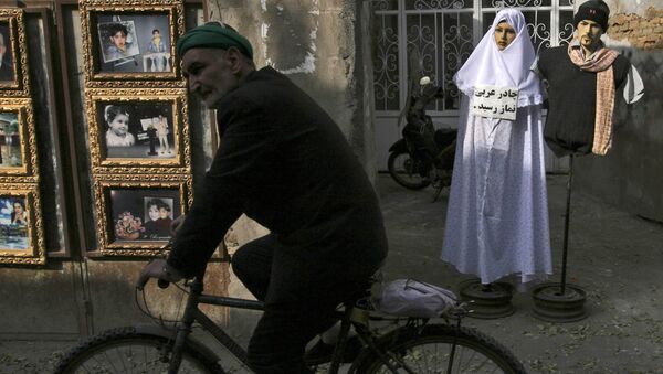 An Iranian Muslim man rides his bike as he passes unidentified photos of pilgrims in Mashhad, 900 km (540 miles) in northeastern Tehran, Iran - اسپوتنیک ایران  