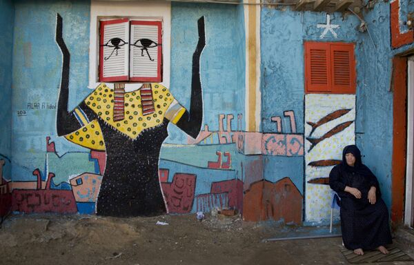 زنی نشسته در زمینه نقاشی  دیواری  آلوئه عبولا حماده  هنرمند مصری در شهر البرلس - اسپوتنیک ایران  