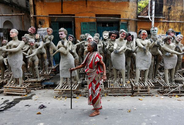 زنی در کنار  مجسمه نیمه تمام  پرسوناژ های  هندو در فستیوال  « کالی پوجا» در  کلکته - اسپوتنیک ایران  
