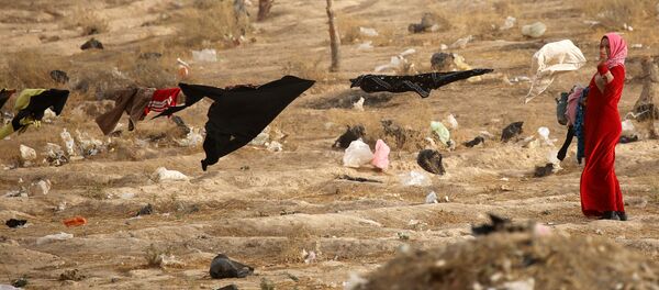 Женщина снимает белье в лагере беженцев близ Мосула Женщина снимает белье в лагере беженцев близ Мосула - اسپوتنیک ایران