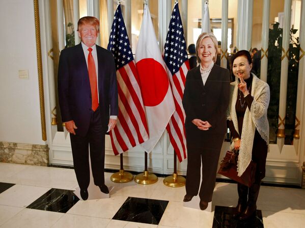 زنی در حال عکس گرفتن با پرتره دونالد ترامپ و هیلاری کلینتون در توکیو - اسپوتنیک ایران  