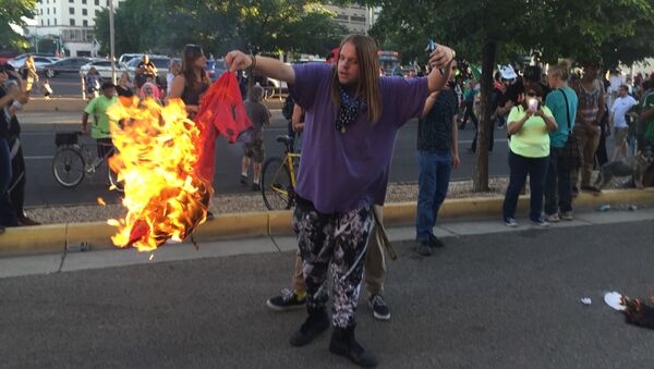 Протестующий с горящий футболкой во время акции протеста против кандидата в президенты США Дональда Трампа в городе Альбукерке - اسپوتنیک ایران  