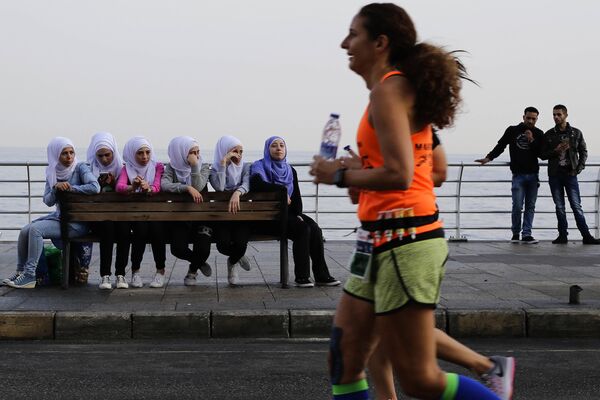 دختر با حجاب در حال تماشای ورزشکار دو شهری در ساحل بیروت در لبنان - اسپوتنیک ایران  