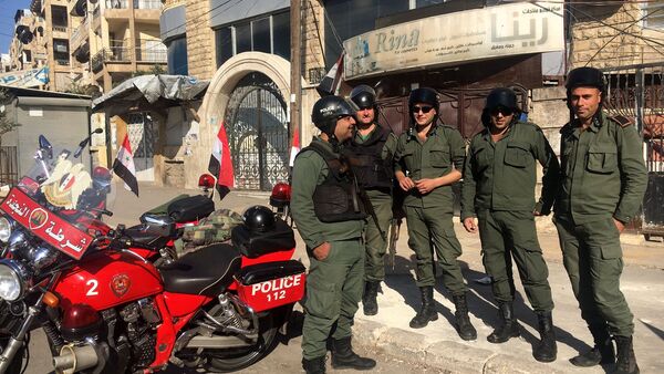 Сотрудники правоохранительных органов дежурят в районе гуманитарного коридора, подготовленного для вывода мирных жителей и боевиков, в восточном Алеппо в Сирии - اسپوتنیک ایران  