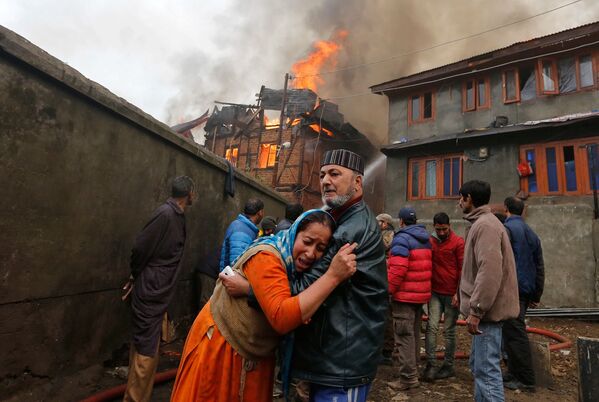 مردی در حال آرام کردن زن گریان در  زمان آتش سوزی در  یکی از خانه های سرینگر هند - اسپوتنیک ایران  
