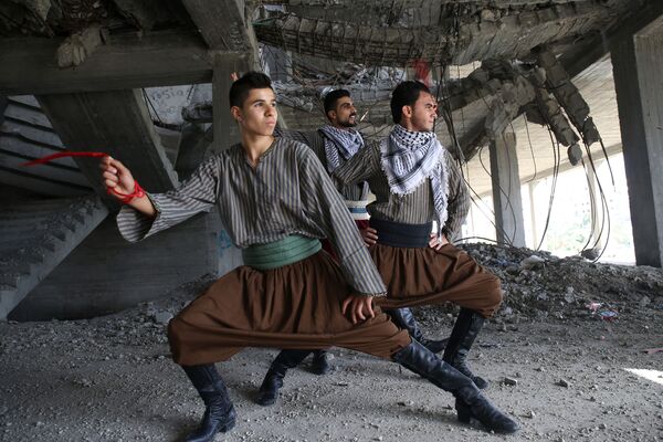 رقاصان فلسطینی در حال اجرای رقص سنتی « دبکه» در ساختمان ویران شده شهر نوار غزه - اسپوتنیک ایران  