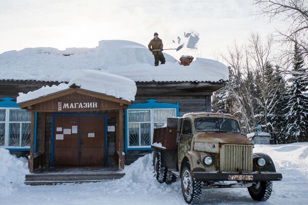 مردی در حال پاک کردن بام مغازه از برف در قصبه « بابروف» روسیه - اسپوتنیک ایران  