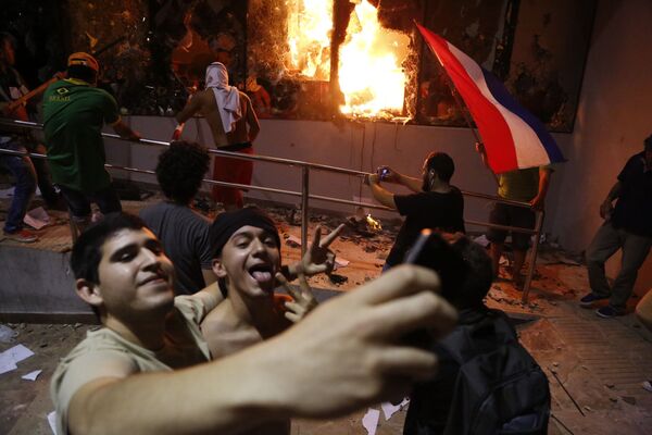 مردی در حال گرفتن عکس در مقابل  ساختمان کنگره در زمان درگیری با پلیس  پس از اعلام نتایج  انتخابات در شهر « آسونسون»  پاراگوئه - اسپوتنیک ایران  