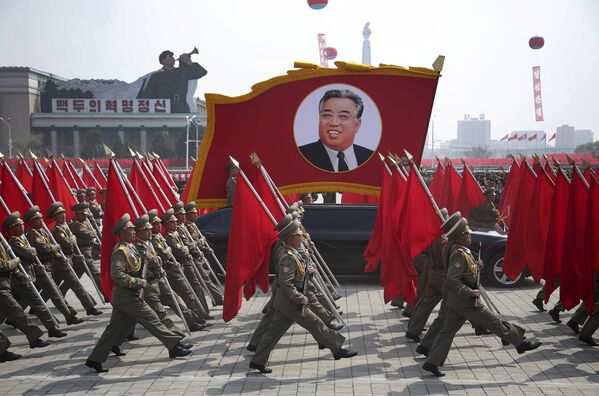 سربازان ارتش کره شمالی در مراسم رژه نظامی 15 آوریل به مناسبت 105 مین سالگرد تولد کیم ایل سونگ بنیادگذار این کشور با پرچم ها در دست رژه می روند - اسپوتنیک ایران  