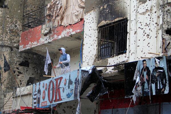 مردی روی بالکن ساختمانی پر از اثرات تیرباران در اردوگاه  پناهجویان در نزدیکی شهر  « سعید» لبنان - اسپوتنیک ایران  