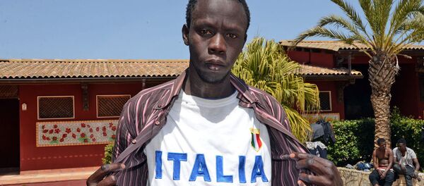 Мигрант позирует в футболке с надписью Italia после прибытия в иммиграционный центр Palazzolo Acreide - اسپوتنیک ایران  