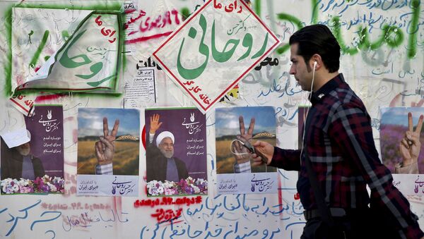 In this Wednesday, May 10, 2017 photo, an Iranian man walks past electoral posters and hand written slogans for presidential election candidates in downtown Tehran, Iran - اسپوتنیک ایران  