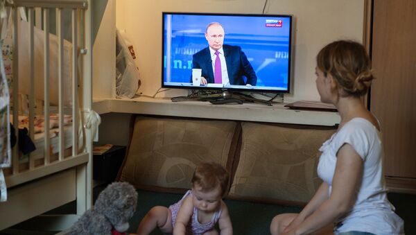 Мать с ребенком смотрит трансляцию Прямой линии с Владимиром Путиным в Омске - اسپوتنیک ایران  