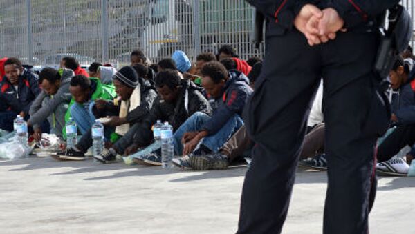 Итальянский полицейский охраняет мигрантов, ожидающих в порту Лампедуза парома до Сицилии - اسپوتنیک ایران  