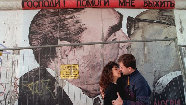 Two unidentified tourists kiss in front of a painting on one of the rare remaing parts of the Wall in Berlin, in October 1995 - اسپوتنیک ایران  