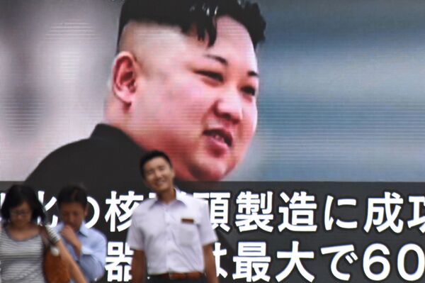 Пешеходы проходят мимо огромного экрана с изображением северокорейского лидера Ким Чен Ына в Токио, Япония - اسپوتنیک ایران  