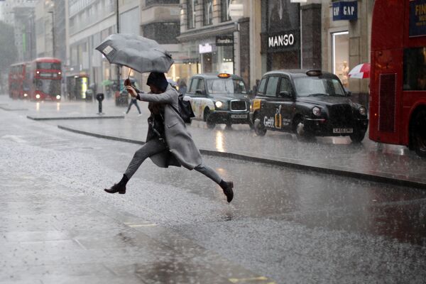 پرش بلند دختر انگلیسی از روی گودال آب  در هنگام بارش باران در لندن - اسپوتنیک ایران  