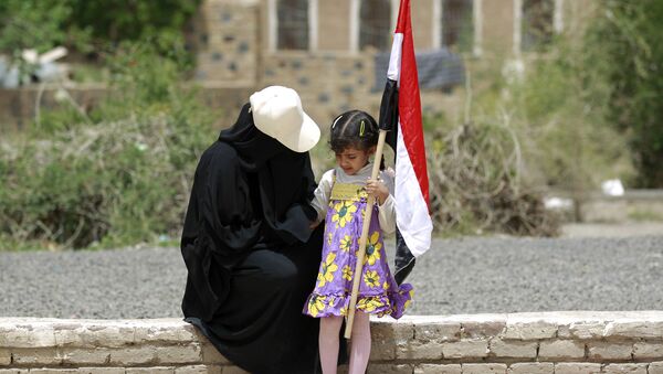 Йеменские женщина и ребенок, держащий национальный флаг, у стены во время митинга в Сане - اسپوتنیک ایران  