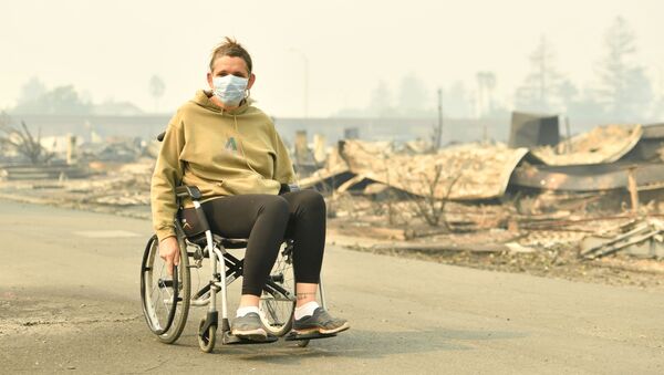 دختری نشسته بر روی ویلچیر در شهر سانتا رزا پس از آتش سوزی مهیب در کالیفرنیا - آمریکا - اسپوتنیک ایران  