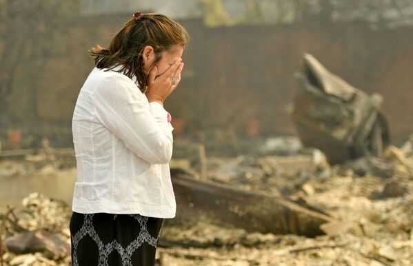 زنی در حال اشک ریختن در کنار خانه سوخته شده خود در شهر سانتا رزا، کالیفرنیا - آمریکا - اسپوتنیک ایران  
