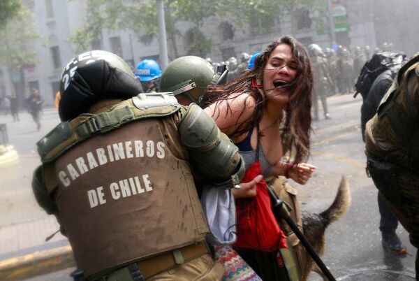 درگیری تظاهرکنندگان با پلیس در راه پیمایی اعتراضی روز کلومبا در سانتیاگو، شیلی - اسپوتنیک ایران  