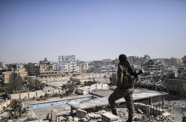 یکی از نیروهای حزب دموکراتیک سوریه در حال تماشای شهر رقه پس از آزادسازی این شهر از تصرف گروهک تروریستی  داعش - اسپوتنیک ایران  