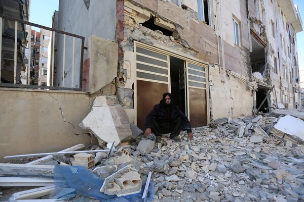 مردی نشسته در کنار در خانه ویران بر اثر زلزله کرمانشاه - اسپوتنیک ایران  