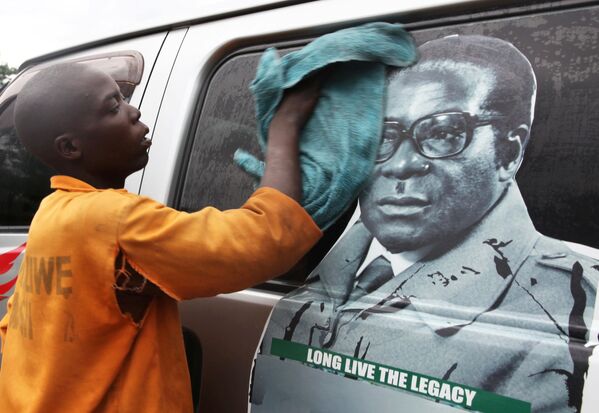 پسری در حال  تمیز کردن شیشه های یک خوردو که تصور رابرت موگابه رئیس جمهور زیمبابوه بر روی آن قرار گرفته - اسپوتنیک ایران  