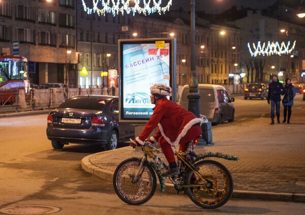مردی با لباس بابانوئل روی دوچرخه در یکی از خیابان های سن پترزبورگ - اسپوتنیک ایران  