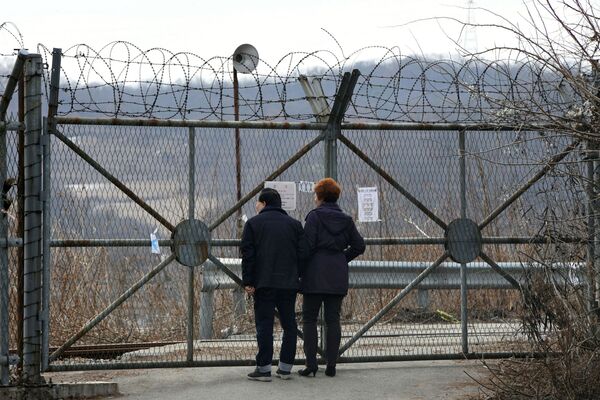 زوجی نزدیک دیوار حول منطقه ی خلع سلاح هسته ای بین کره شمالی و جنوبی - اسپوتنیک ایران  