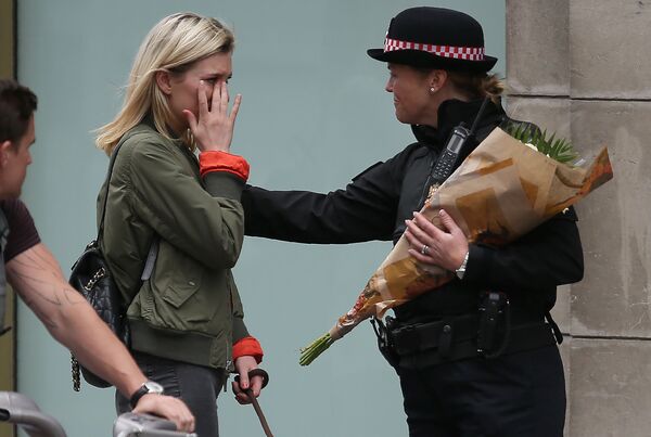 زنی از پلیس می خواهد تا گل ها را به یاد قربانیان حمله ی تروریستی روی پل لندن ببرد - اسپوتنیک ایران  