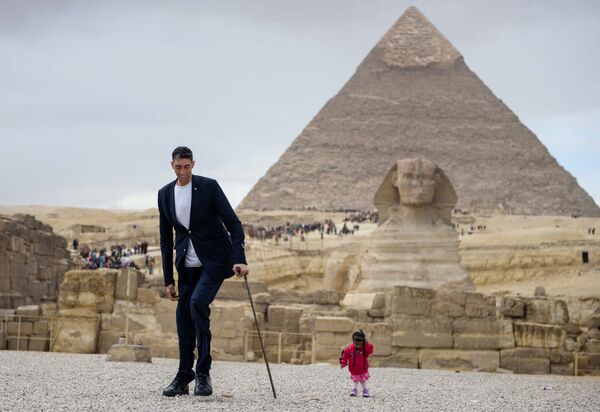 سلطان کنن بلند قدترین مرد دنیا  از ترکیه و جوتی آمگه کوتاهترین زن دنیا از هند در نمایی از اهرام ثلاثه در مصر - اسپوتنیک ایران  