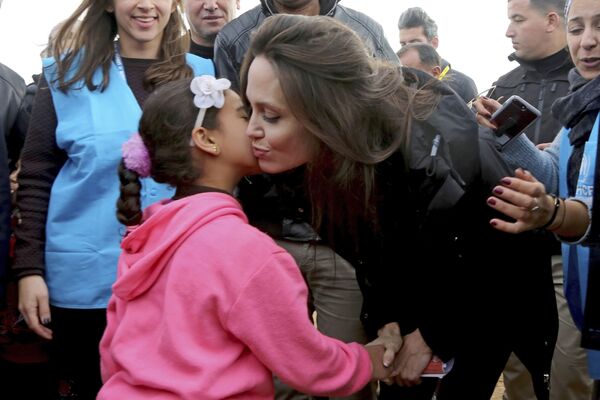 آنجلینا جولی بازیگر هالیوود و سفیر صلح سازمان ملل در بازدید از اردوگاه پناهندگان سوری در حال بوسیدن یک دختر سوری - اسپوتنیک ایران  
