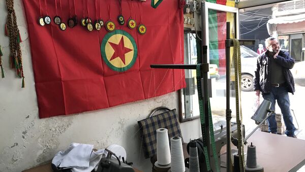پرچم ها و اشیای دارای  نمادهای گردان های مدافع خلق (YPJ) کردها در یک کارگاه دوزندگی در شهر عفرین سوریه - اسپوتنیک ایران  