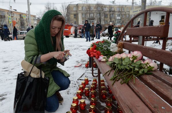 زنی در حال روشن کردن شمع به یاد قربانیان آتش سوزی در مرکز تجاری-تفریحی «آلبالوی زمستانی» در کمروو روسیه - اسپوتنیک ایران  