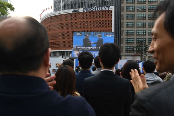 مردم در سئول در حال تماشای دست دادن رهبران کره شمالی و جنوبی - اسپوتنیک ایران  