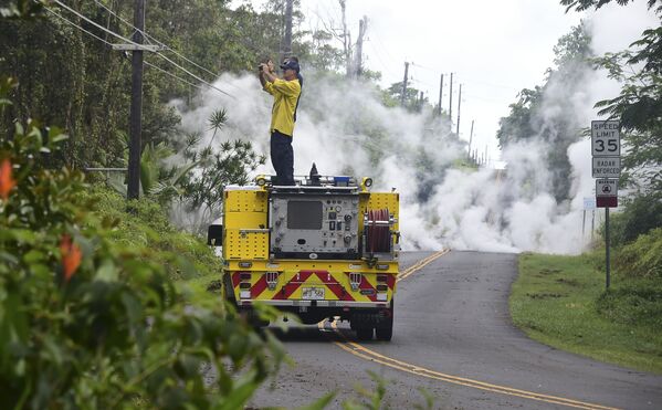 مأمور آتش نشانی  در حال عکاسی از  دود برخاتسه پس از فوران کوه آتشفشان « کیلائوئه» در هاوایی - اسپوتنیک ایران  