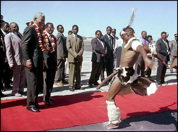 نلسون ماندلا رئیس جمهور آفریقای جنوبی و رئیس جمهور زیمباوه در حال تماشای رقص در فرودگاه هراره ۱۹۹۷ - اسپوتنیک ایران  