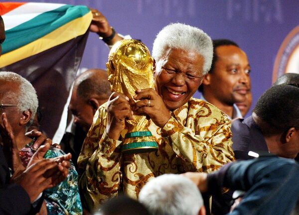 نلسون ماندلا رئیس جمهور سابق آفریقای جنوبی که جامی از جام جهانی فوتبال در زوریخ را در دستانش دارد. سال ۲۰۰۴ - اسپوتنیک ایران  