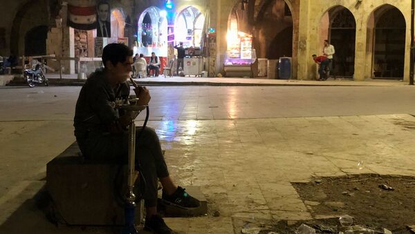 مردی در حال کشیدن قلیان در میدانی نزدیک بازار در حلب - اسپوتنیک ایران  