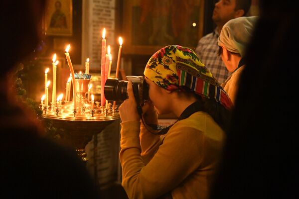زنی در حال عکس گرفتن از مراسم تولد حضرت مسیح در ولادی واستوک - اسپوتنیک ایران  