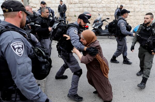 زن فلسطینی سعی میکند از میان پلیس های اسرائیلی عبور کند - اسپوتنیک ایران  