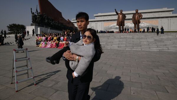 مردی با بچه اش در جشن روز تولد کیم ایل سونگ در کره شمالی - اسپوتنیک ایران  